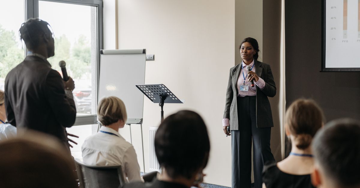Professional business conference presentation with diverse participants engaging in communication.